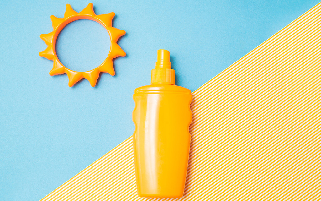 Bottle of sunscreen cream or lotion with sun toy flat lay on the blue and yellow background with copy space. Spf summer skin, uv protect top view